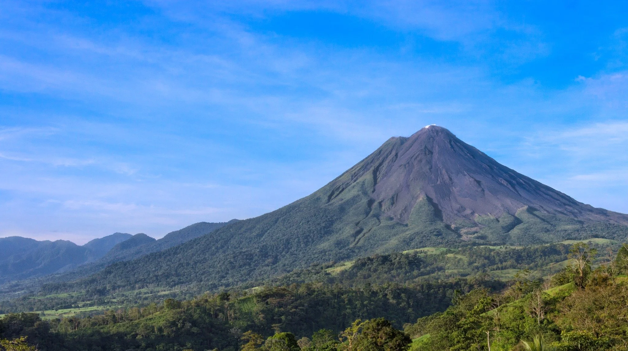 Scenic view of Arenal Volcano surrounded by lush greenery in Costa Rica.