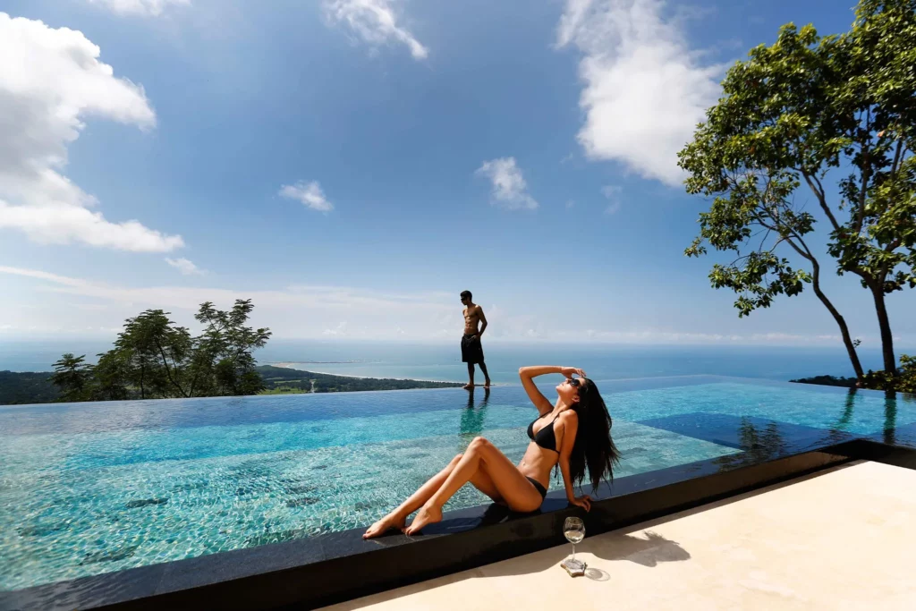 Luxurious infinity pool in Costa Rica with a stunning ocean view, a man and woman relaxing, showcasing crstours’ top-notch experiences."